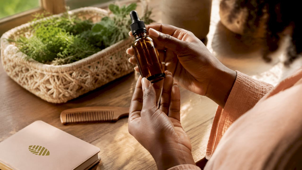 Hands holding jojoba oil bottle for scalp hydration