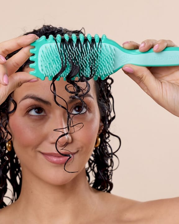 Man detangling curly hair in home shower