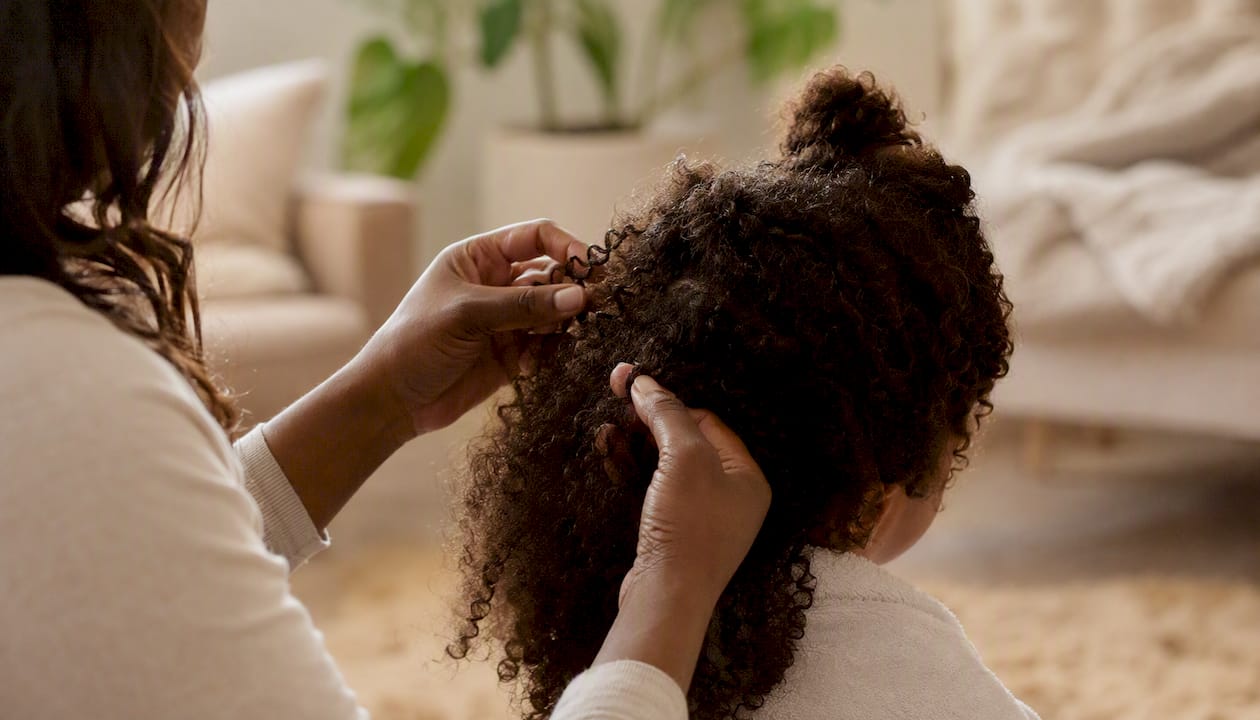 Hands gently detangling knot in curly hair