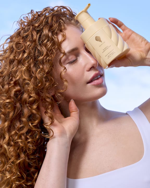 Hands scrunching wavy hair wrapped in cotton t-shirt