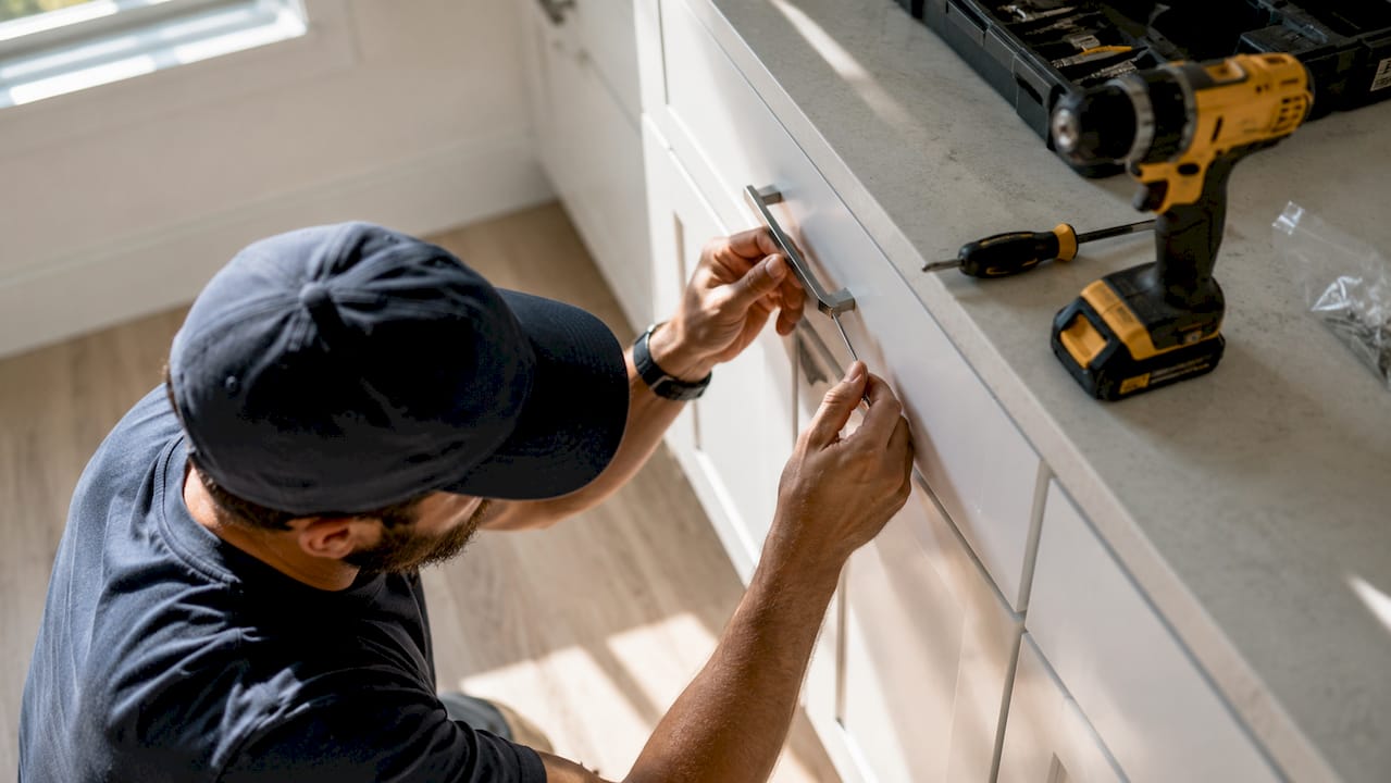 Hands installing cabinet hardware in rental kitchen