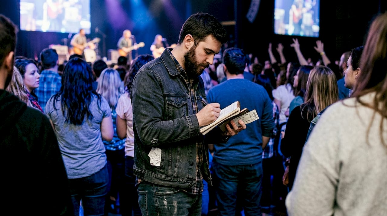 Man jotting notes at live concert