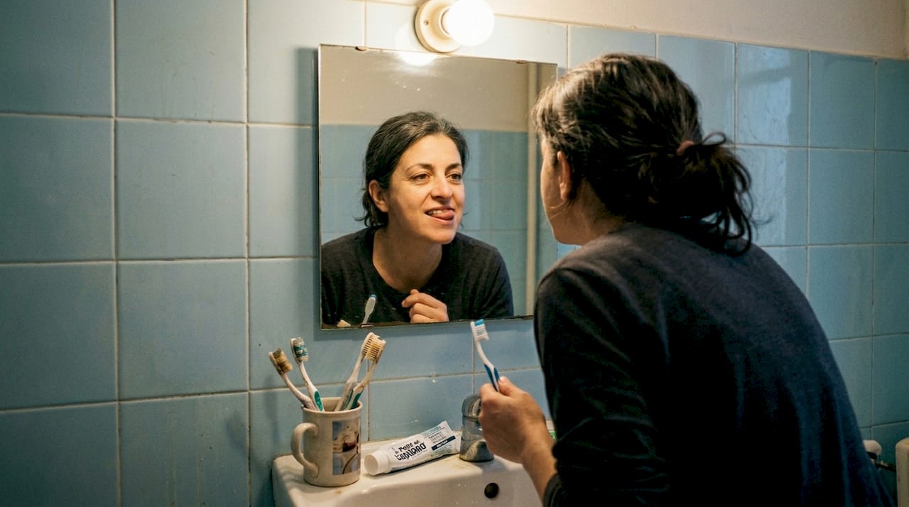 Una donna si osserva le gengive allo specchio per controllare la propria salute orale.