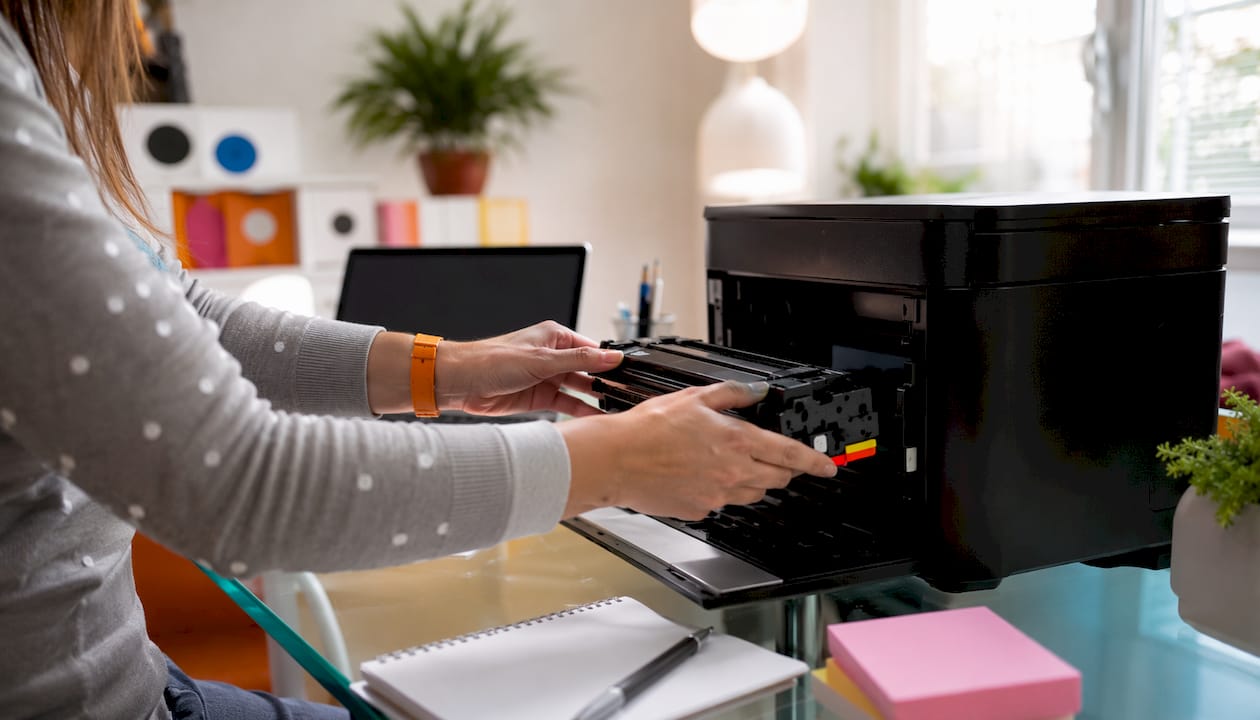 Mãos a colocar um cartucho de toner numa impressora laser