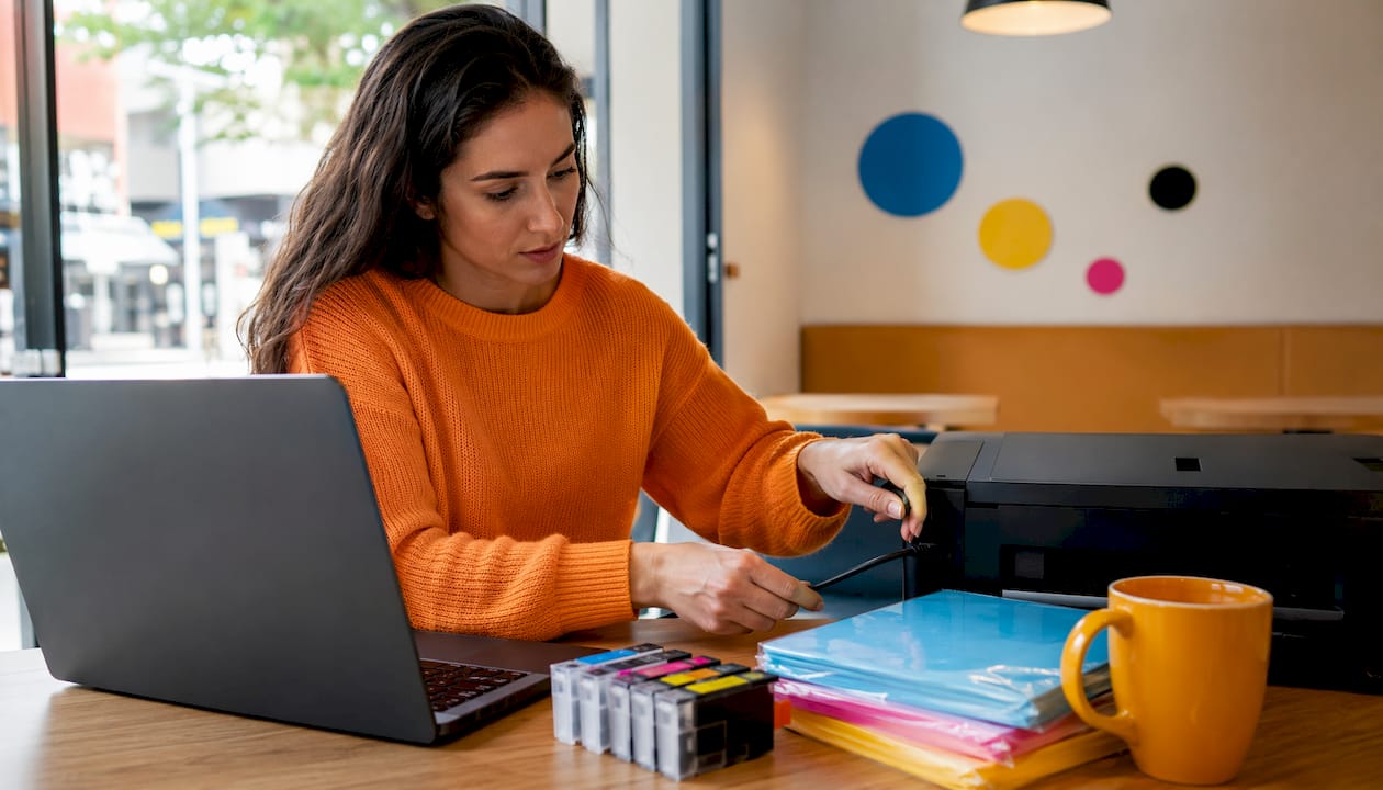 Uma colaboradora confere os consumíveis da impressora no escritório.