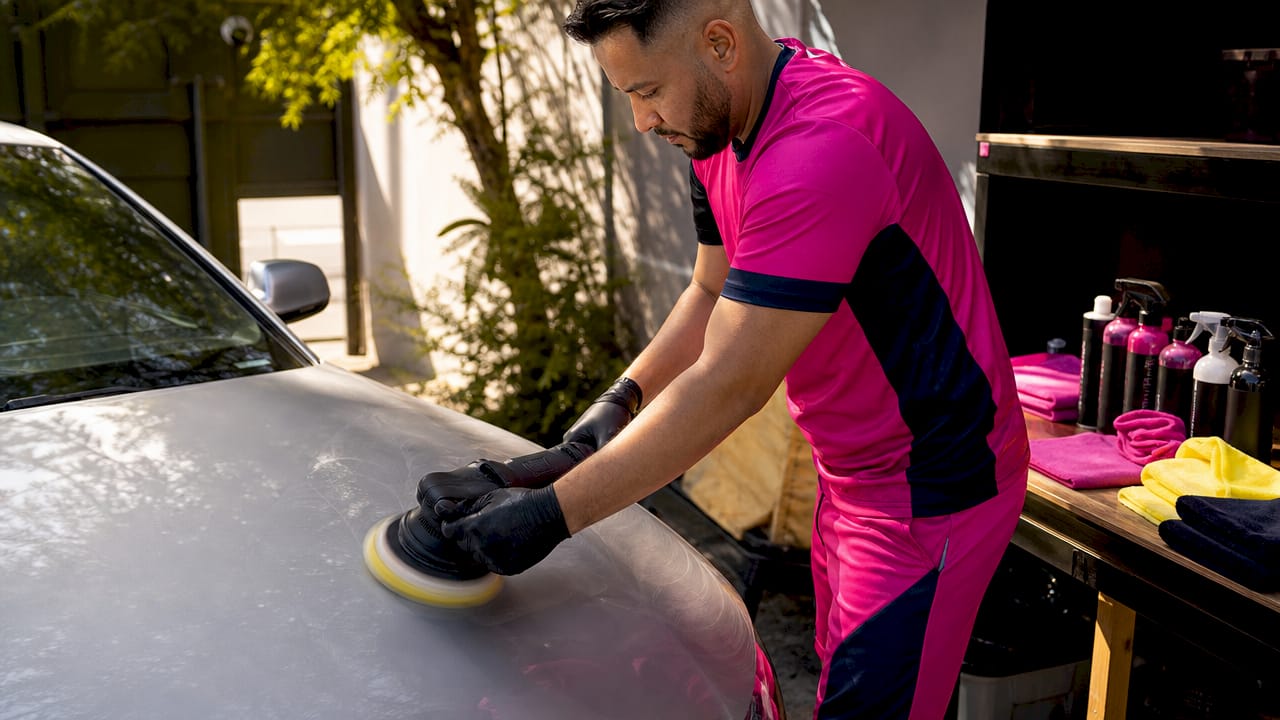 Hands using dual-action polisher on car hood