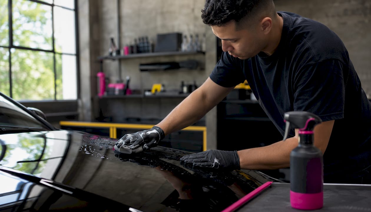 Hands using clay bar on car paint surface