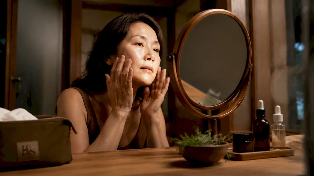 Woman applying skin serum at vanity