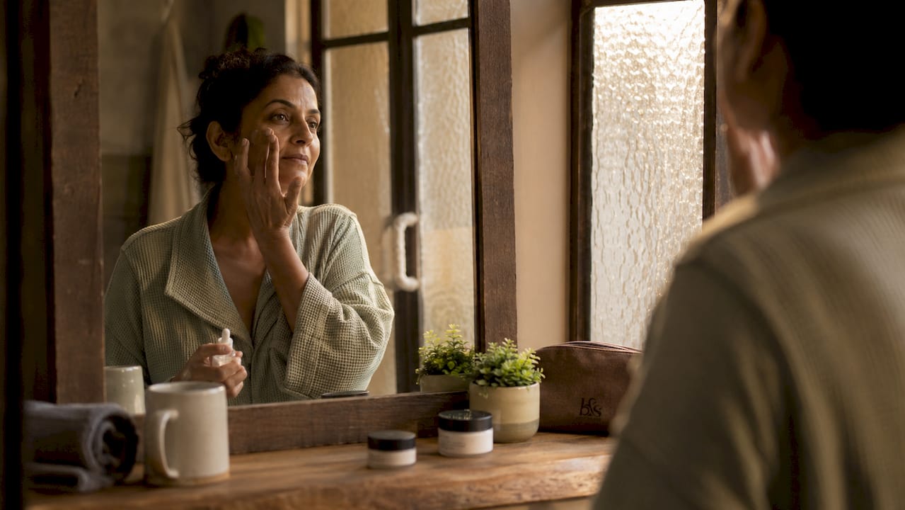 Woman applying serum in bathroom mirror