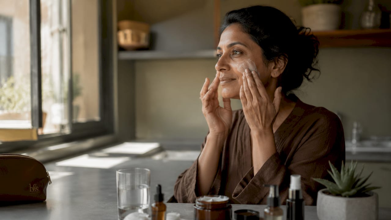 Woman applying moisturizer in bathroom