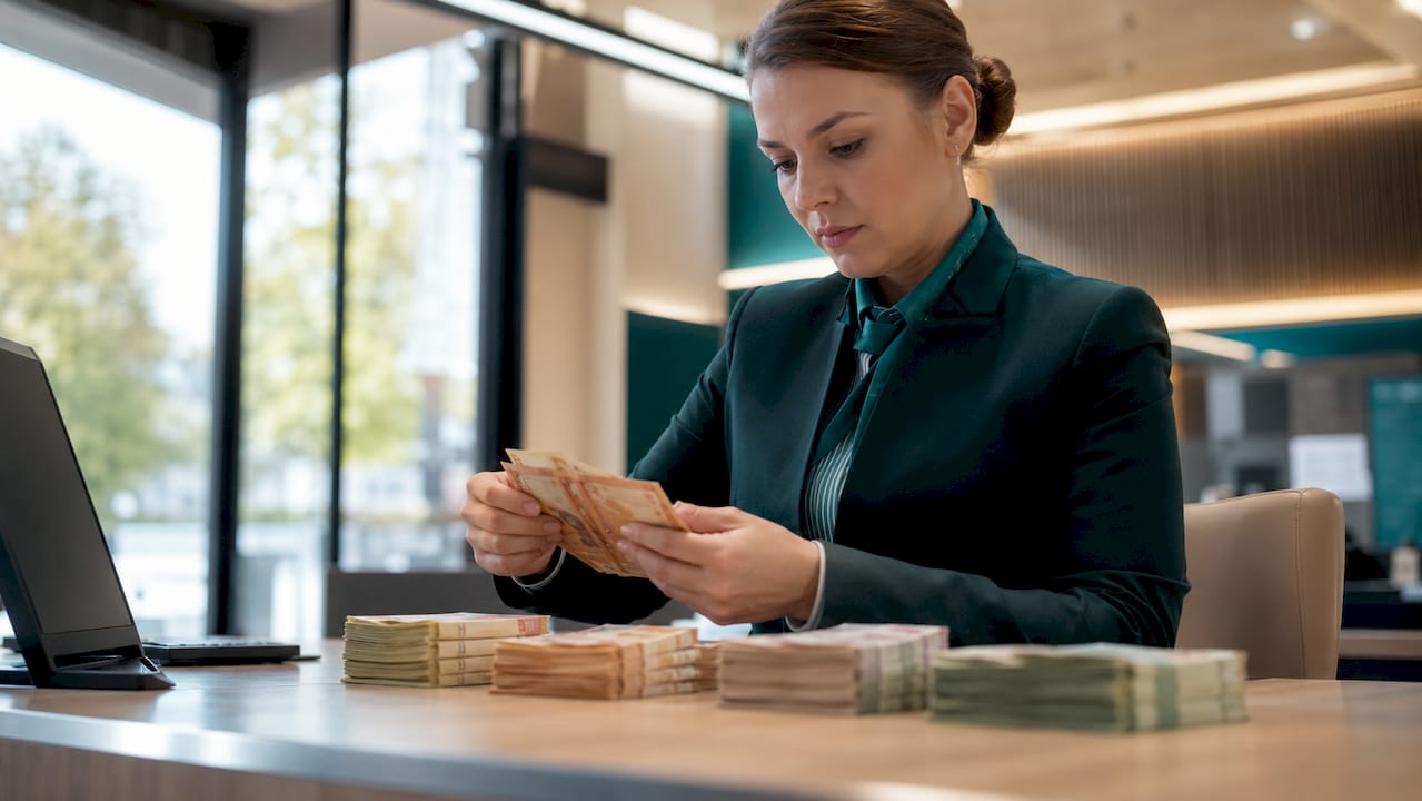 Banko darbuotojas skaičiuoja grynuosius pinigus valiutos keitykloje.