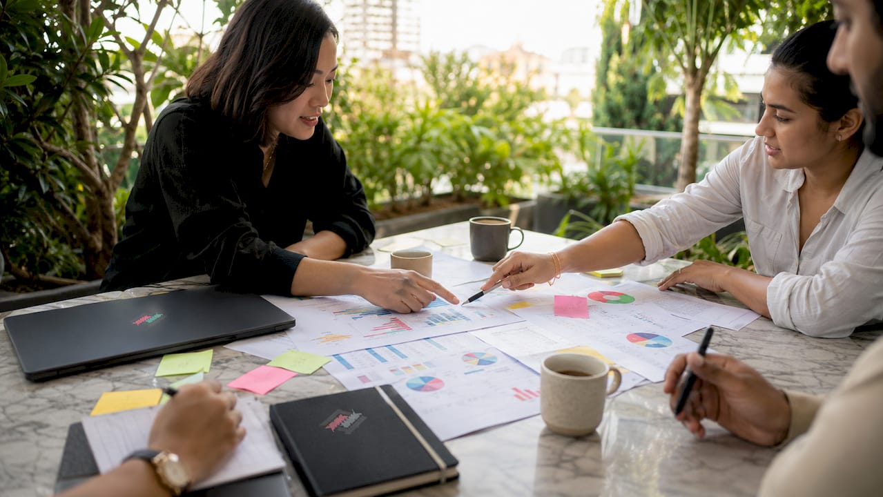 Overhead shot hands discussing fintech compliance charts