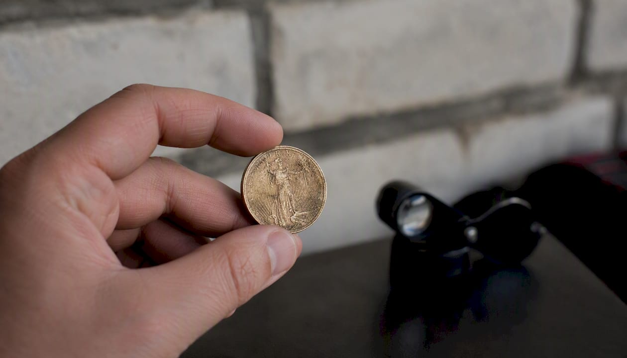 Rankoje laikoma nudėvėta investicinė moneta iš arti