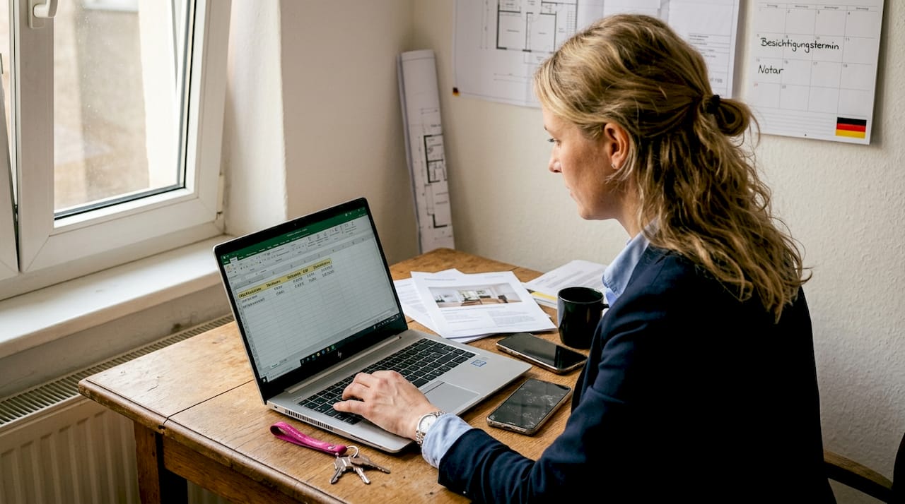 Eine Immobilienmaklerin ermittelt am Laptop den passenden Verkaufspreis.