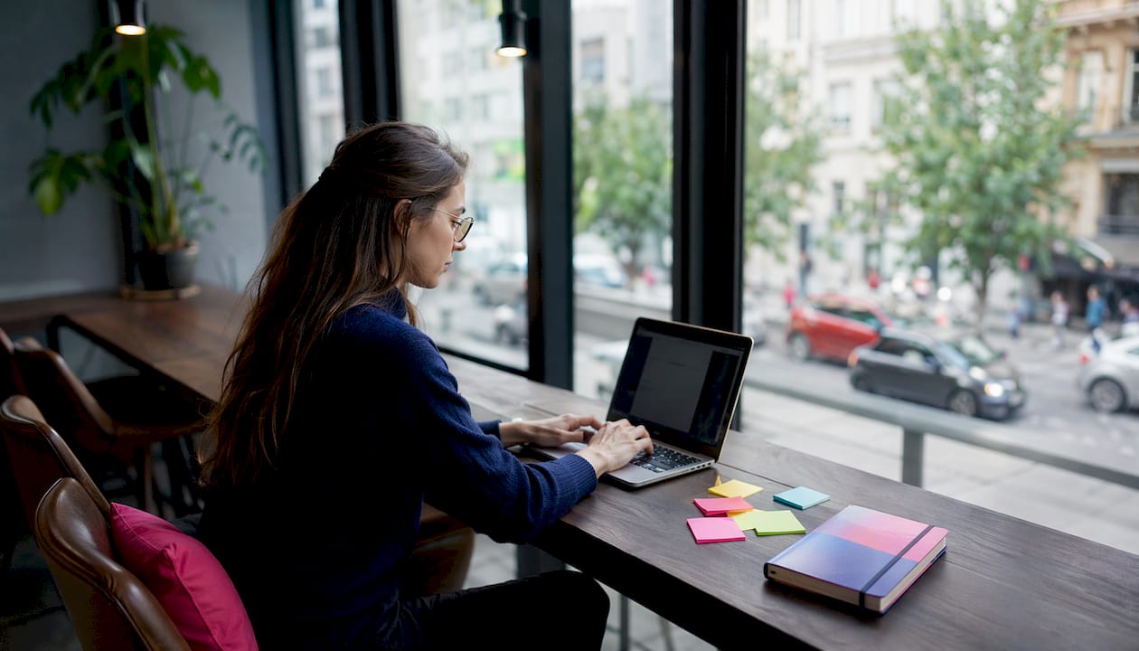 Eine Frau arbeitet im Homeoffice und tippt konzentriert auf ihrem Laptop.