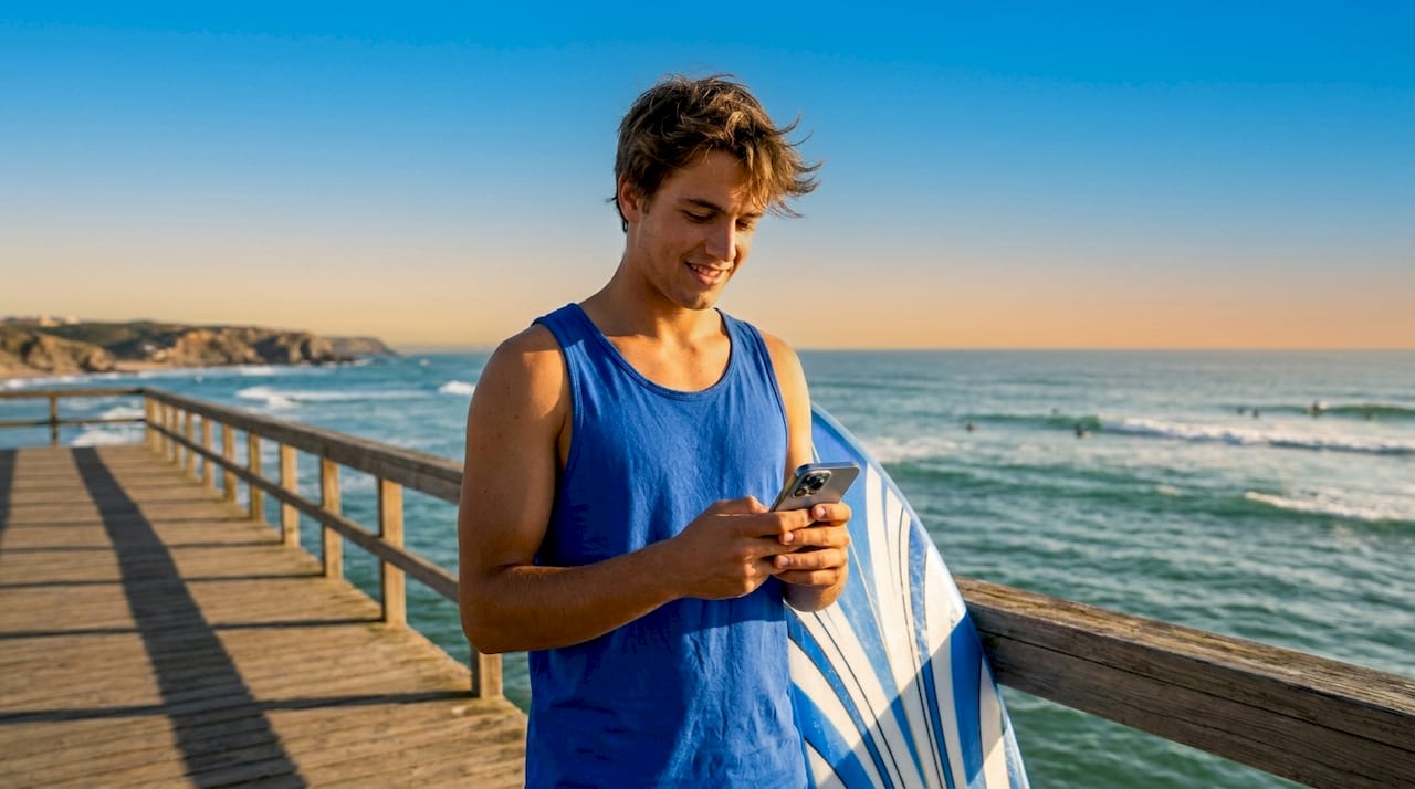 Surfer checking surf app on smartphone by ocean