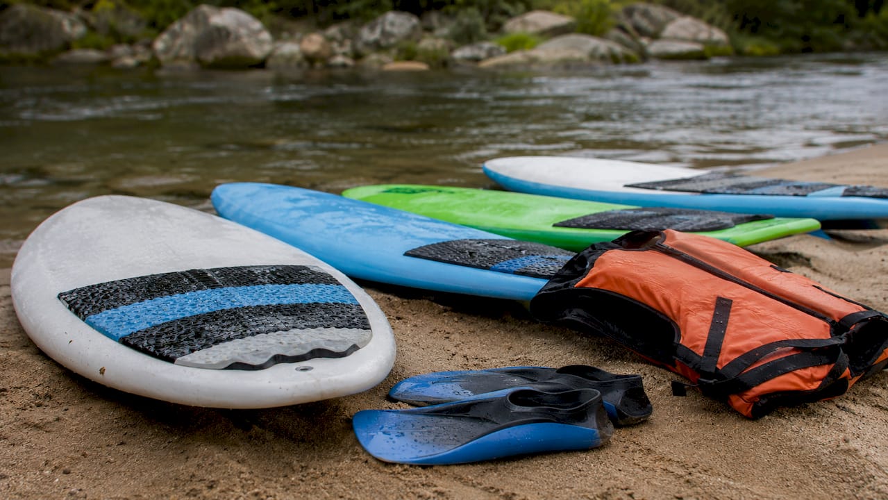 Row of river surfboards and safety gear on grass