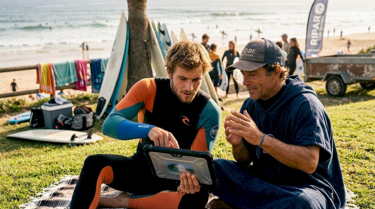Surfer and coach reviewing surf video footage