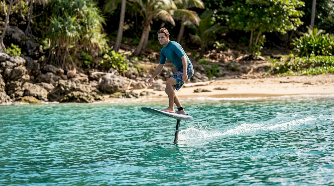 Surfer riding foil surfboard over water
