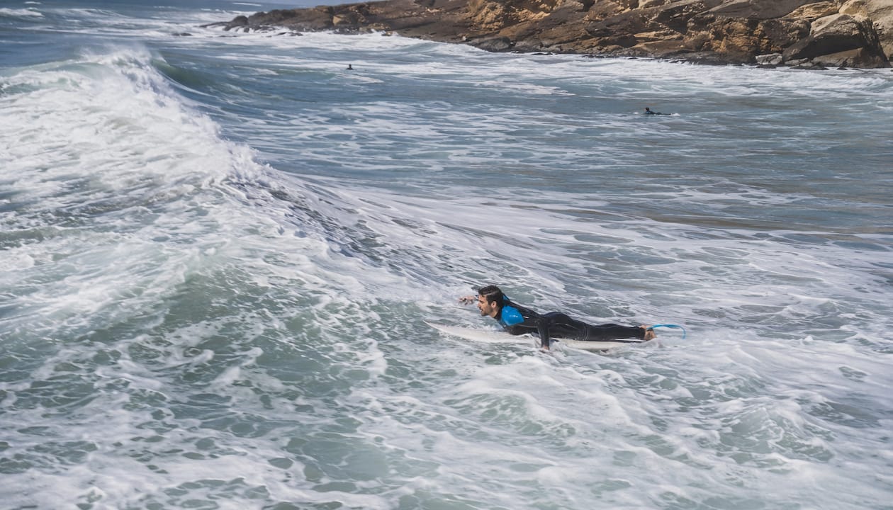 Surfer paddling into large wave at Peniche