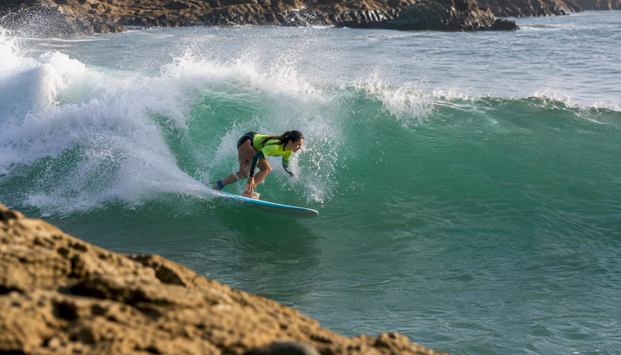 Female surfer executing bottom turn on wave