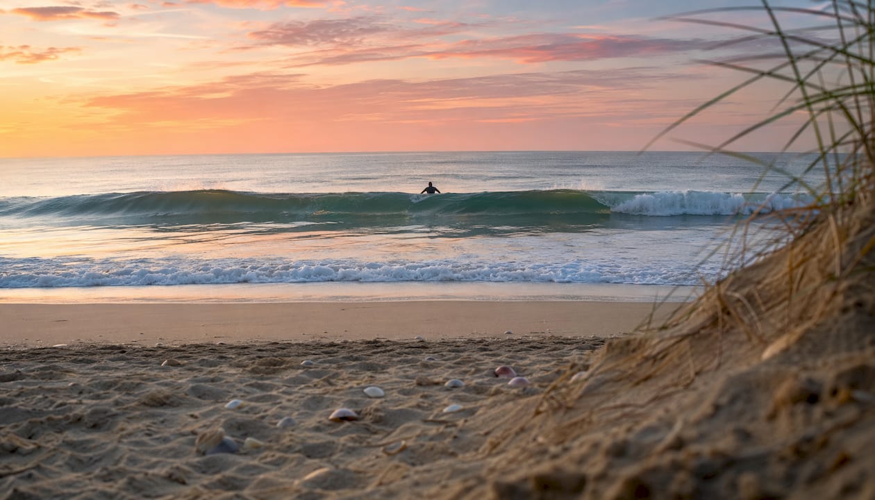 Glassy surf waves forming at dawn with lone surfer