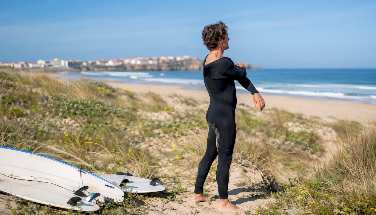 Surfer putting on wetsuit at Peniche beach