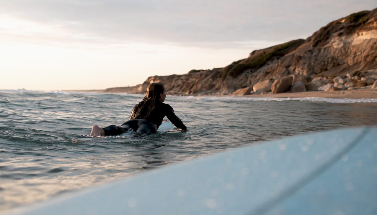 Woman paddling on surfboard at Portuguese beach