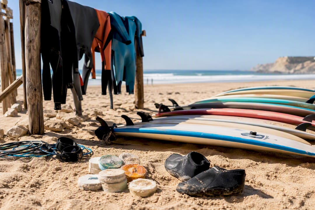 Soft-top longboards and wetsuits arranged on sandy beach