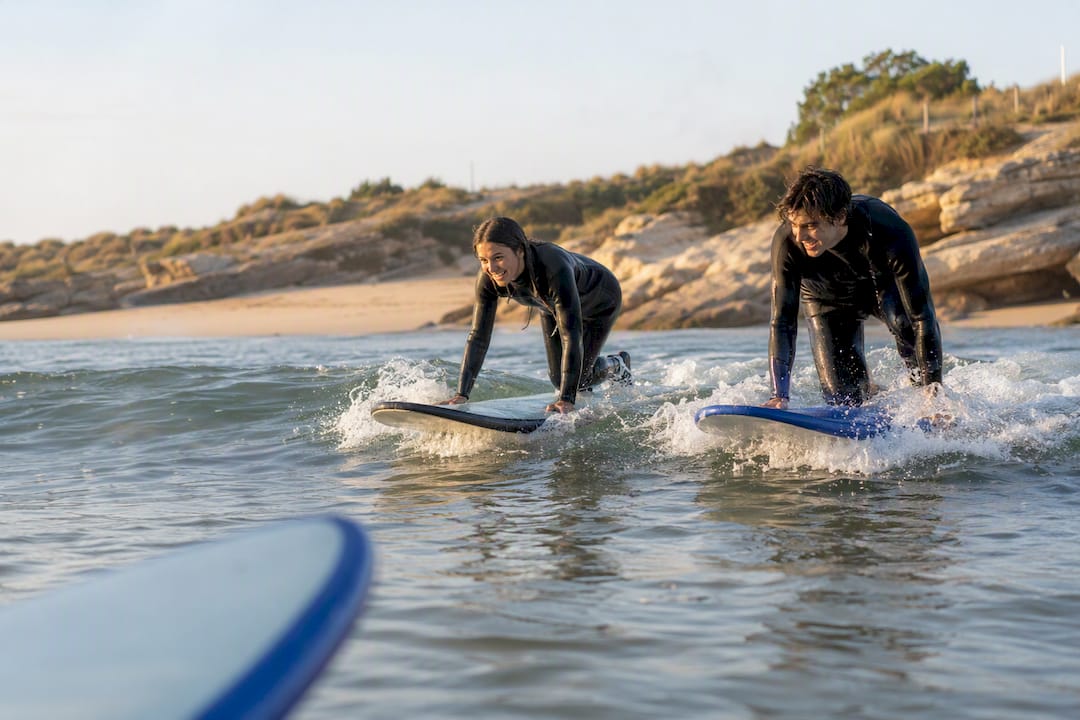 Couple pop-up surfing small waves on Portuguese beach