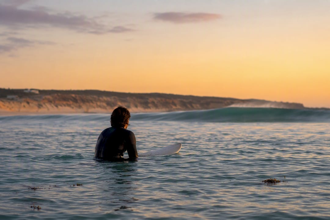 Surfer watching a wave at sunset