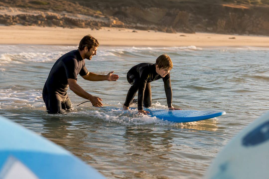 Surf instructor assisting beginner pop-up in shallow water