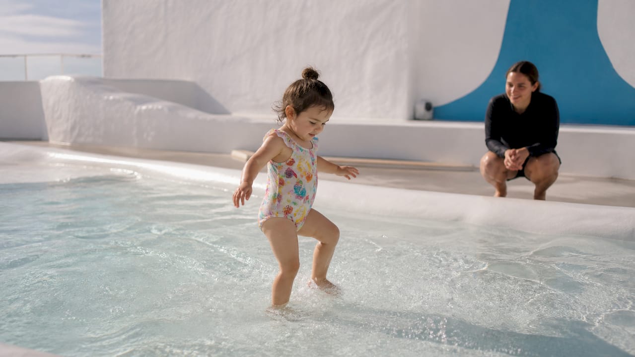 Child cautiously facing small waves in pool