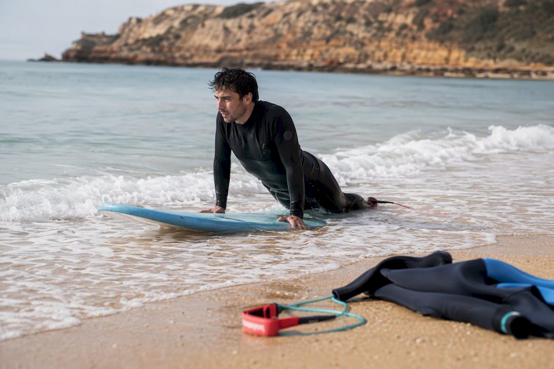 Beginner surfer popping up on board in Portugal