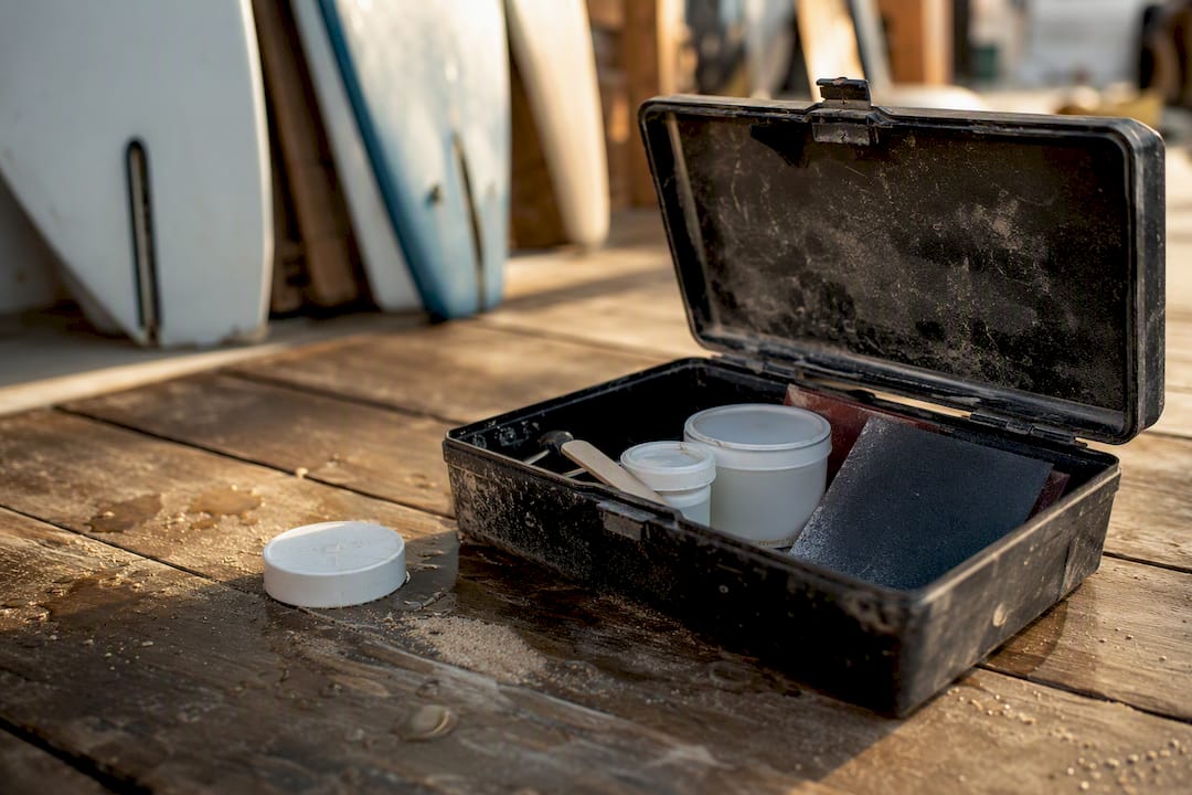 Surfboard ding repair kit on wooden deck