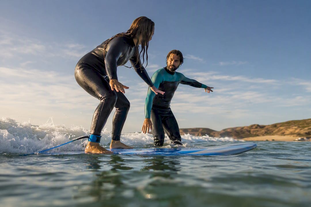 Instructor coaching beginner in Praia Areia Branca waves