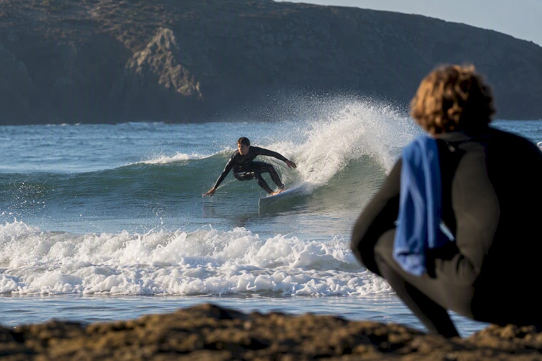 Coach observing intermediate surfer on wave