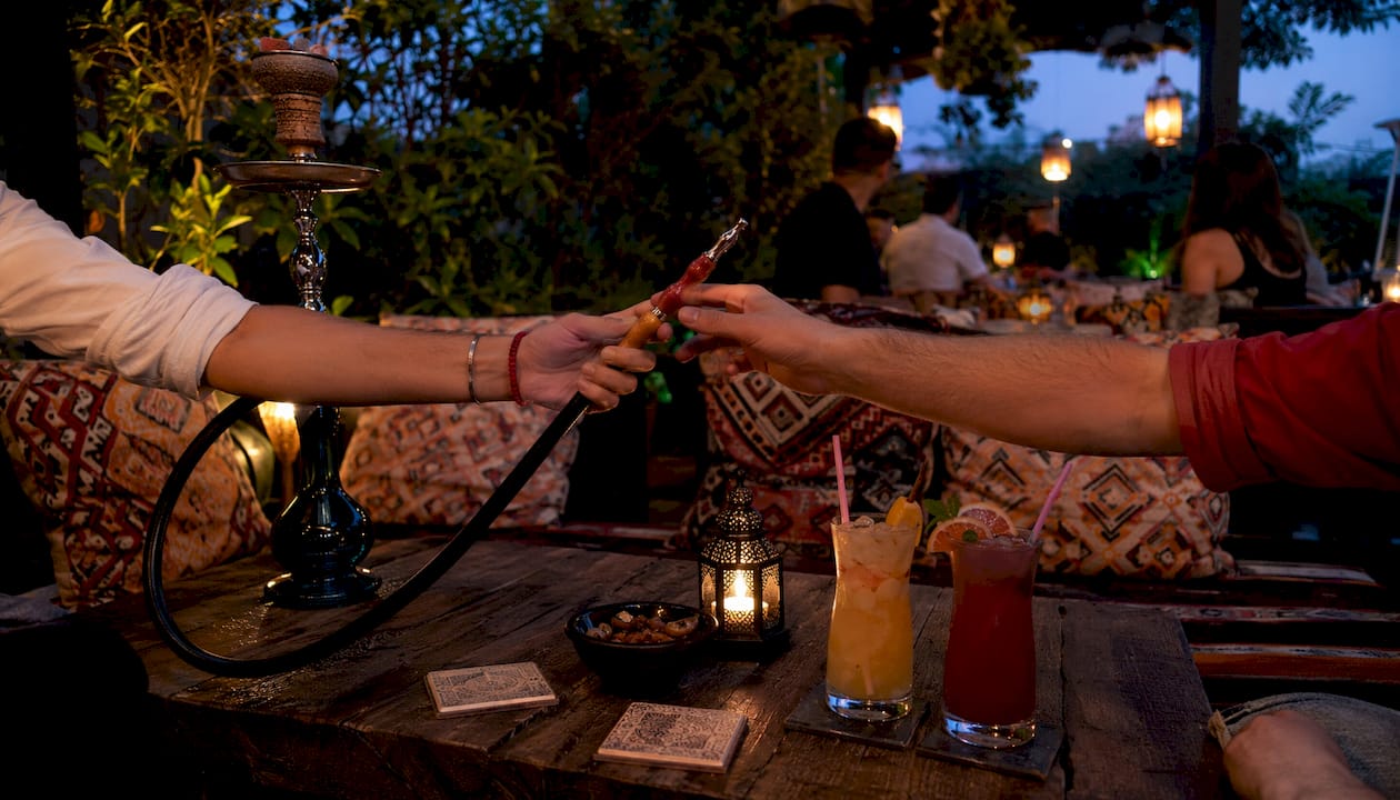 Hands passing shisha hose over bar counter