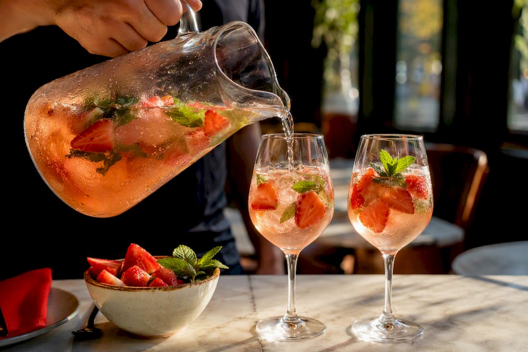 Rosé sangria poured with strawberries and mint