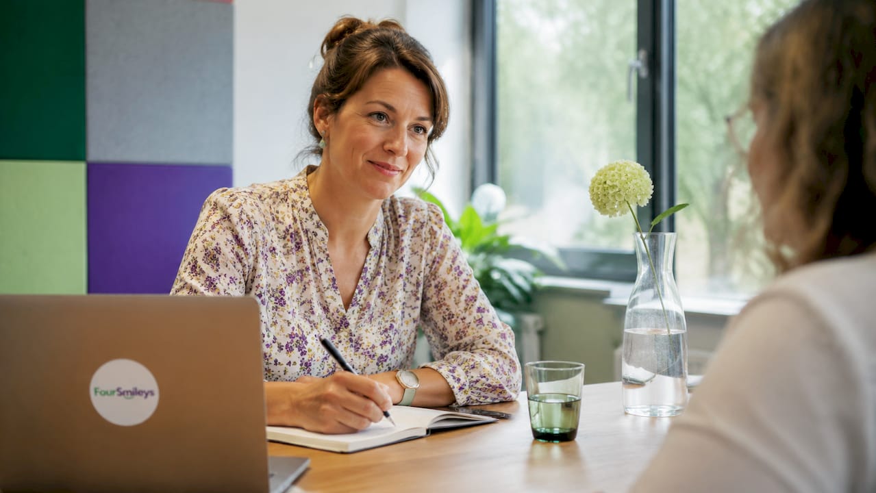 Tijdens het gesprek schrijft een vrouw haar bevindingen en opmerkingen op.
