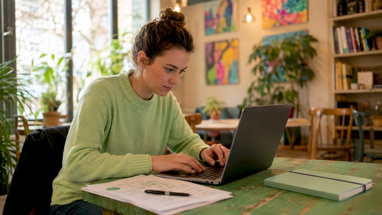 Een vrouw werkt op haar laptop aan het opstellen van vragen voor een enquête.