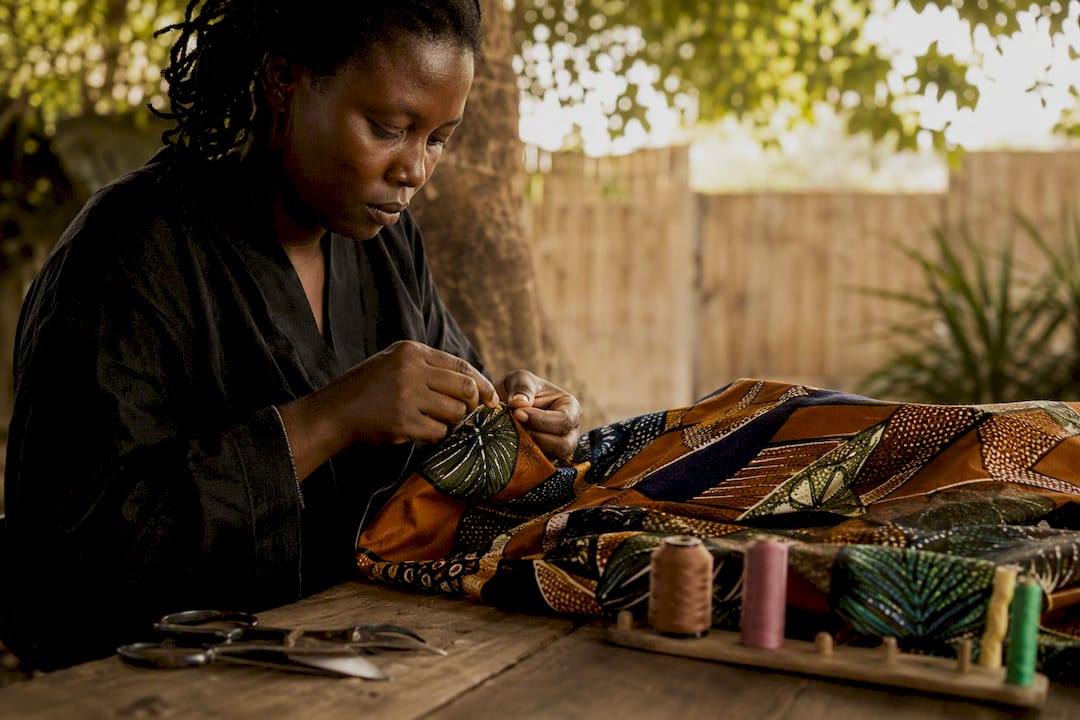 Artisan hands stitching vibrant West African fabric