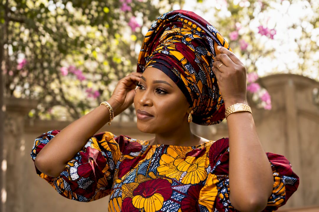 Woman adjusting colorful West African wedding outfit
