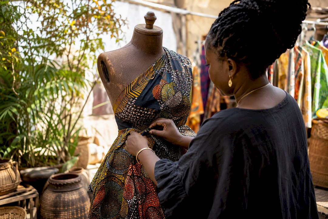 Hands draping African fabric on mannequin torso
