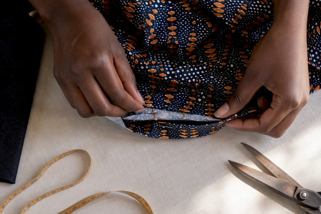 Tailor pinning an Ankara hem adjustment