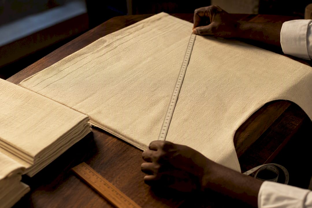 Tailor measuring a wide agbada sleeve