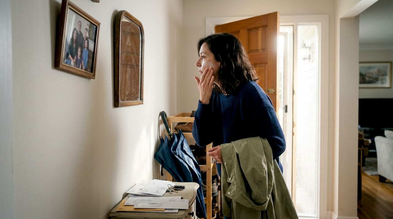 Woman applies sunscreen by front door