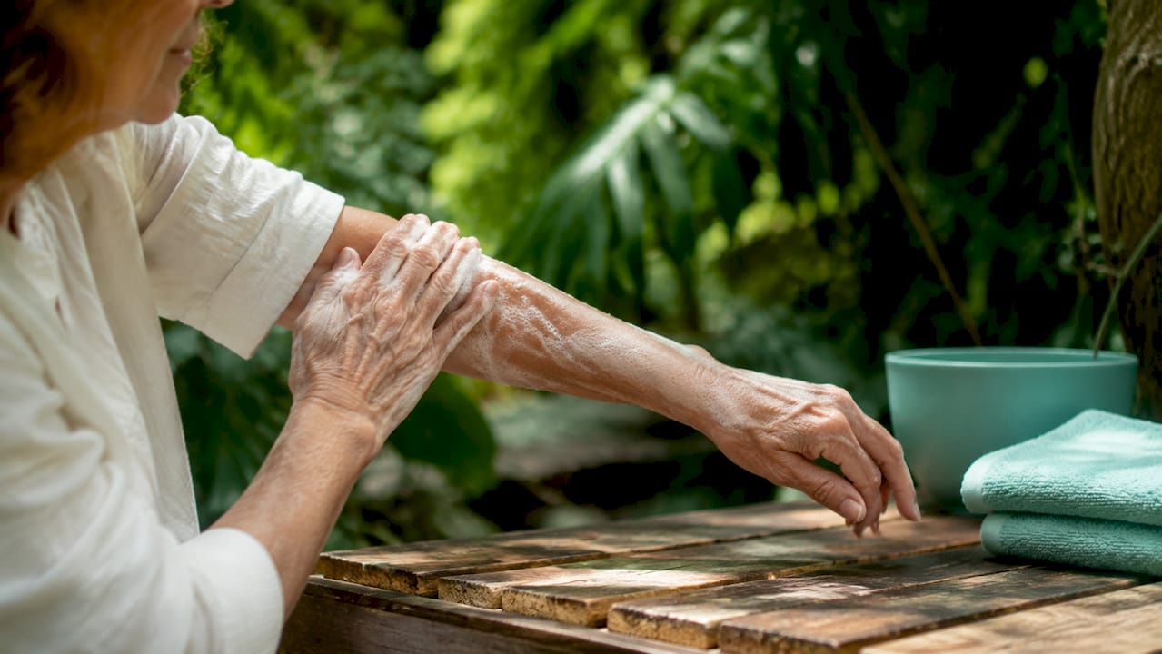 Close-up hands applying cleanser on arm