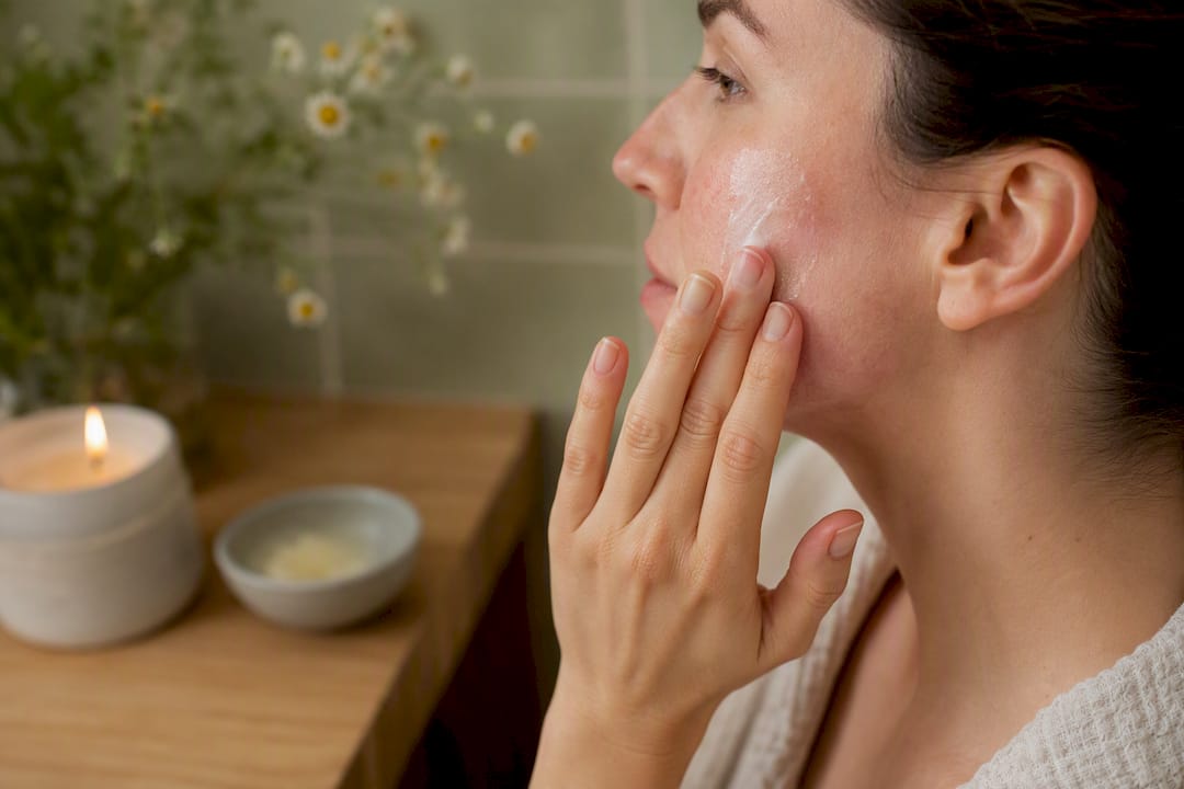 Hands applying moisturizer on irritated facial skin