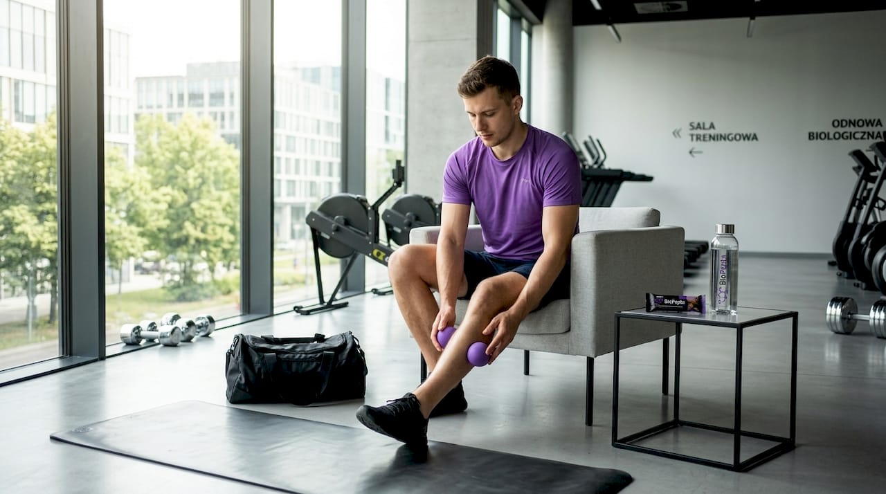 Sportowiec regeneruje się w domu, korzystając z rollera do masażu.